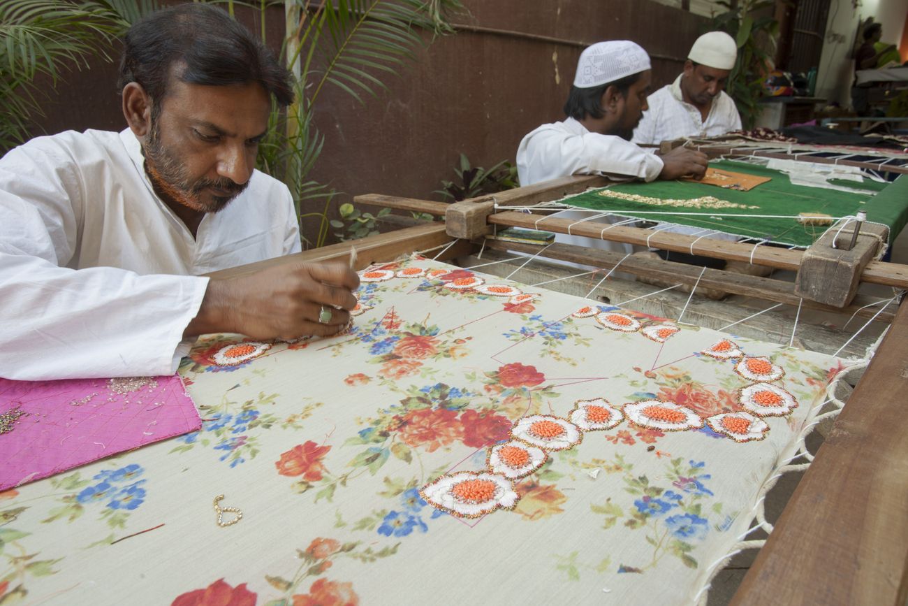 Drei Handwerker besticken Kleidungsstücke, Bangalore