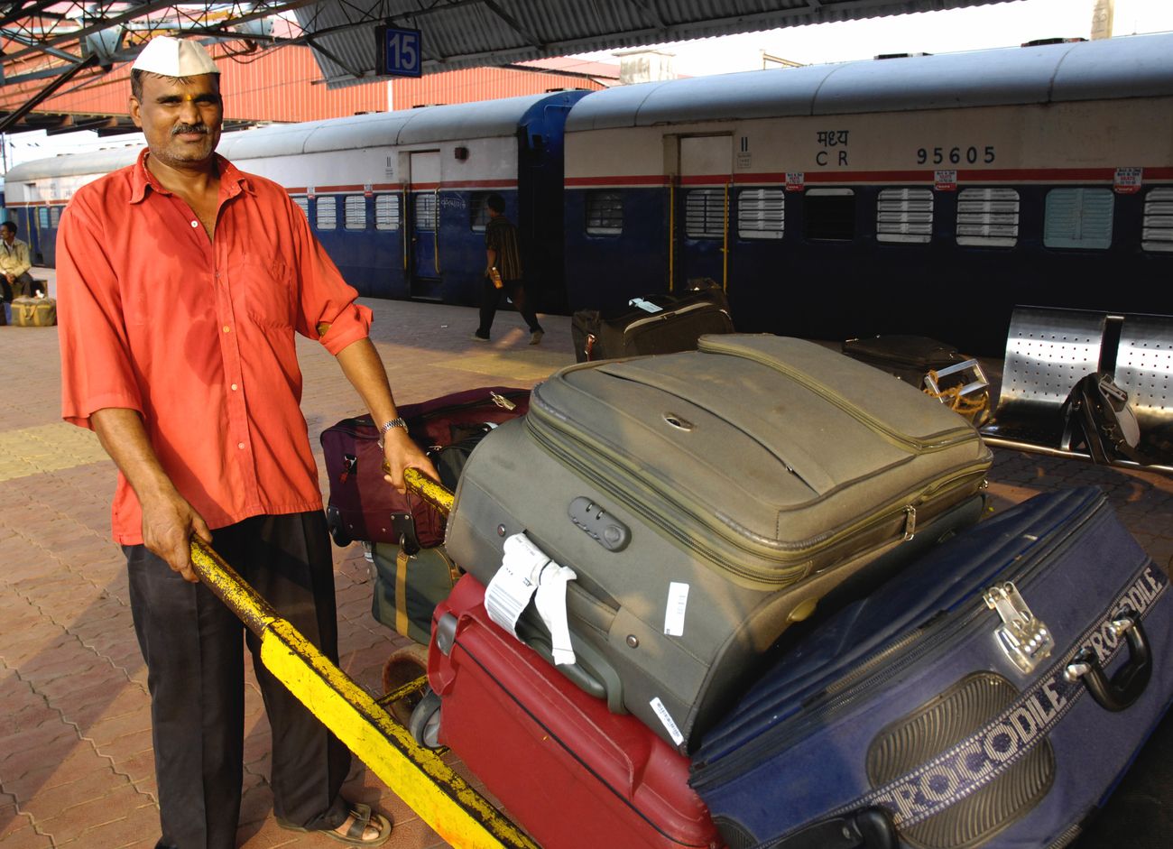 Gepäckträger in roter Universaluniform, der Gepäck von Passagieren trägt