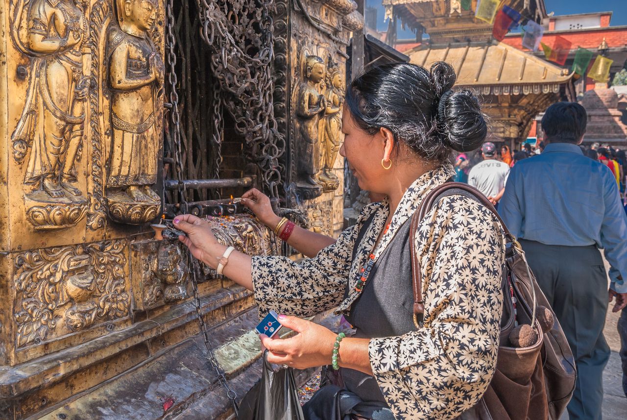 Monkey Temple woman lighting candle for buddha kathmandu
